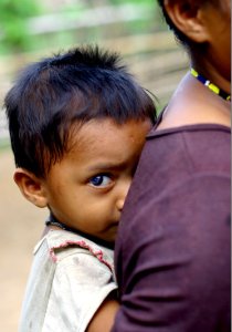 A shy boy hiding behind his mother